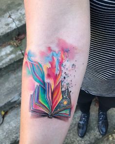 a person with a tattoo on their arm and an open book in the middle of it