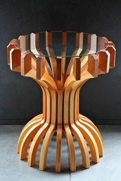 a wooden table with glass top sitting on concrete flooring next to a black wall