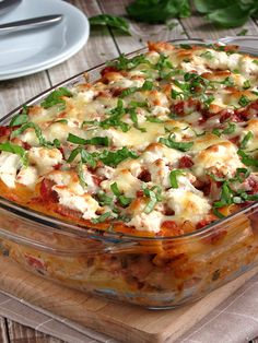 a casserole dish with meat and vegetables in it on a wooden table next to plates