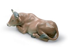 a ceramic cow laying down on the ground