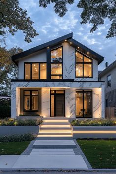 a modern house with stairs leading up to the front door and windows on each side