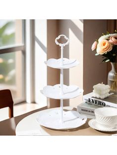 three tier cake stand with flowers in vase on table