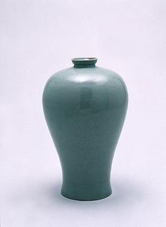 a green vase sitting on top of a white table