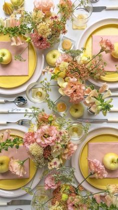 the table is set with yellow plates, pink napkins and flowers in vases