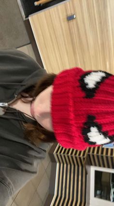 a woman wearing a red knitted hat with black and white designs on the front