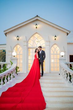 a man and woman in formal wear standing on the steps of a white building at night