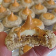 a hand is holding up a cookie with caramel on top and white frosting in the middle