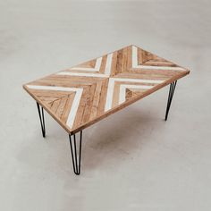 a wooden table with black hairpin legs and white chevron pattern on top, against a gray background