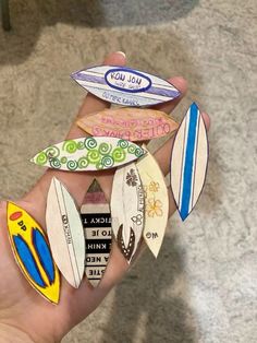 a person holding several different colored surfboards on their fingernails in the palm of their hand