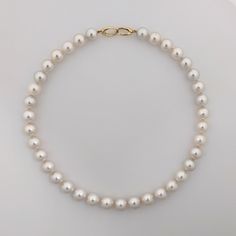 Featuring a high quality White South Sea pearl necklace, this piece secures with a 14K yellow gold interlocking oval clasp. The enticing 100% natural color - a pure white with a gentle hint of pink overtone. Pearls' size ranges from 10.3 to 11.6 mm, and are round or near round in shape. You'll be captivated by their high luster. The surface of the pearls is 85-90% clean, presenting only a few natural blemishes. These small imperfections, or nature's kisses, serve as undeniable evidence of their Fine Jewelry Single Strand White Pearl Necklace, Luxury White Pearl Necklace With Sterling Silver Clasp, Luxury White Single Strand Pearl Necklace, Classic Oval Pearl Necklace, Formal Single Strand Oval Pearl Necklace, Classic Oval Yellow Gold Pearl Necklace, Formal Oval Single Strand Pearl Necklace, Refined White Round Pearl Necklace, Elegant White Oval Pearl Necklace