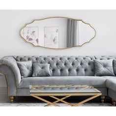 a living room scene with focus on the couch and coffee table, as well as an oval mirror