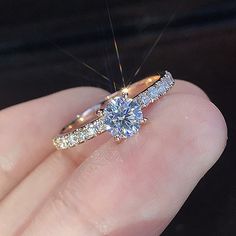 a close up of a person's hand holding a diamond ring