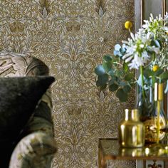 a vase with flowers on a table next to a mirror and couch in a room