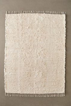 a white rug with fringes on the bottom and sides, against a gray background