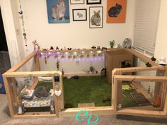 an indoor cat house made out of wood and fake grass with lights strung from the ceiling