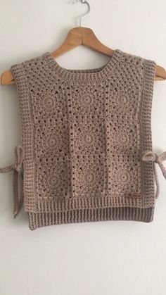 a crocheted sweater hanging on a wooden hanger