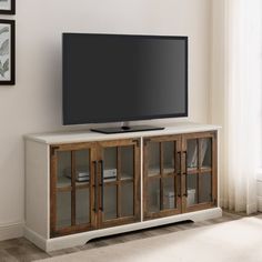 a flat screen tv sitting on top of a wooden entertainment center in a living room