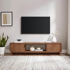 a living room with a large flat screen tv on the wall and two vases in front of it