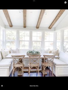 a dining room with white walls and wooden beams