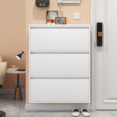 a white dresser sitting next to a chair in a room with beige walls and flooring