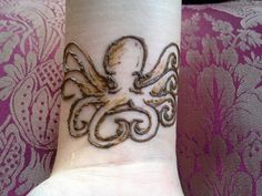 an intricately designed wrist tattoo on a woman's left hand, with gold ink