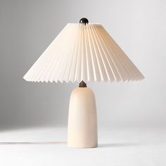 a white table lamp sitting on top of a wooden base