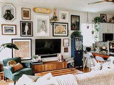 a living room filled with furniture and lots of framed pictures on the wall above it