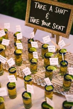 there are many shot glasses with limes in them sitting on the table next to each other