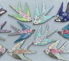 many different colored birds with flowers on them are sitting in a row and one bird has its wings spread out