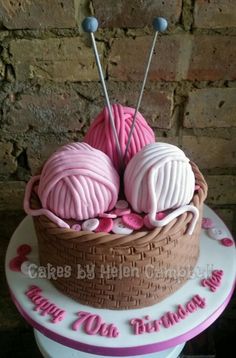 two balls of yarn in a basket on top of a cake that says happy birthday