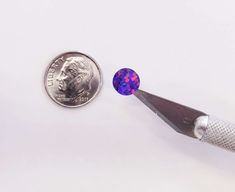 a coin is next to a pair of scissors with a purple diamond in the middle