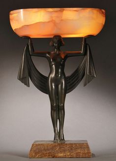 an art deco table lamp with a woman holding a tray on it's back