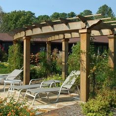 an outdoor seating area with tables and chairs in the foreground, surrounded by greenery