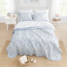 a bed with blue and white bedspread in a bedroom next to a window