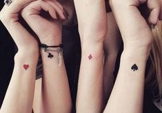 three girls with matching tattoos on their arms holding hands up to each other and looking at the camera