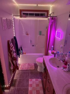 a bathroom with pink lights on the ceiling and rugs in the bathtub area