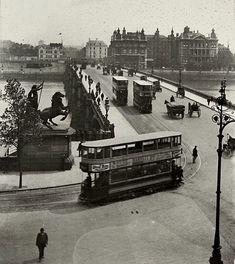 an old black and white photo of buses on a street with people walking around it