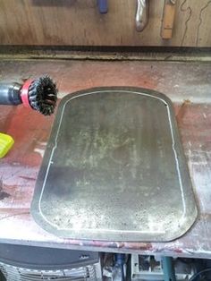 a metal pan sitting on top of a counter next to a brush and screwdriver