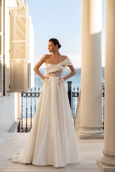 a woman in a wedding dress standing by columns