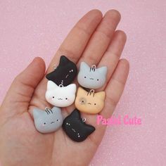 a hand holding five small cat charms in it's palm, with the caption past cutie