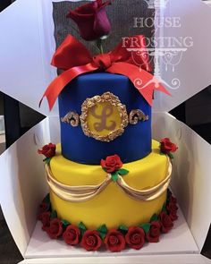 a three tiered cake with red roses on the bottom and gold trimmings