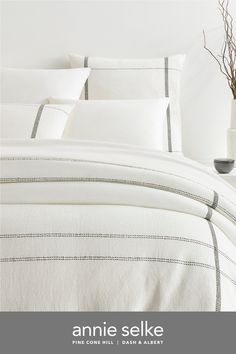 an image of a bed with white linens and grey lines on the comforter