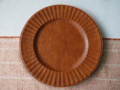 a brown plate sitting on top of a table next to a white and orange rug