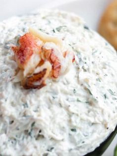 a close up of a bowl of food with some crackers in the back ground