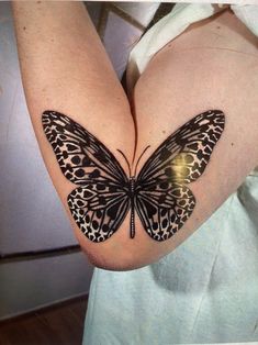 a butterfly tattoo on the back of a woman's left arm and chest,