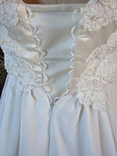 the back of a wedding dress with white flowers on it