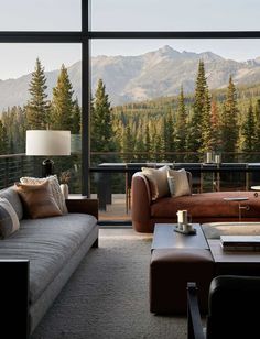 a living room filled with furniture and a large window overlooking the mountains in the distance