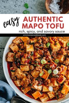 a bowl filled with tofu and sauce on top of a table next to spoons