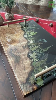 a wooden table topped with a painting on top of a hard wood floor next to a potted plant