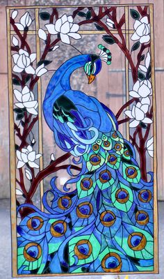 a stained glass window with a blue peacock on it's back and white flowers in the background